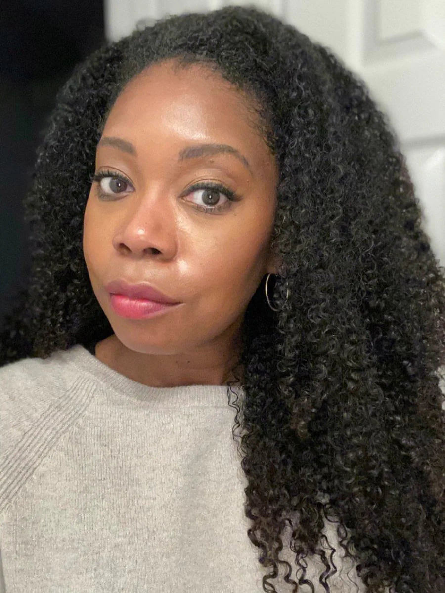 Woman with curly hair wearing a light gray sweater indoors