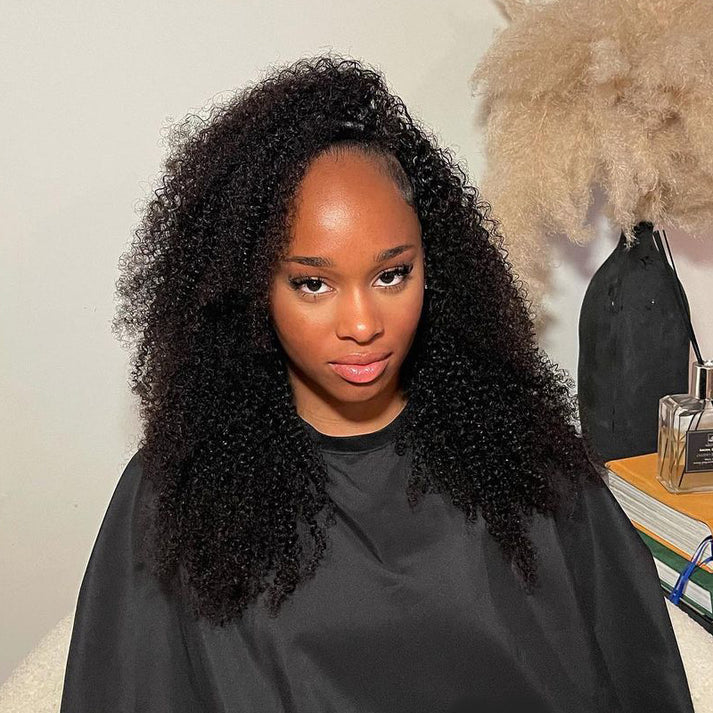 Woman with curly hair wearing a black salon cape, with a curly half wig